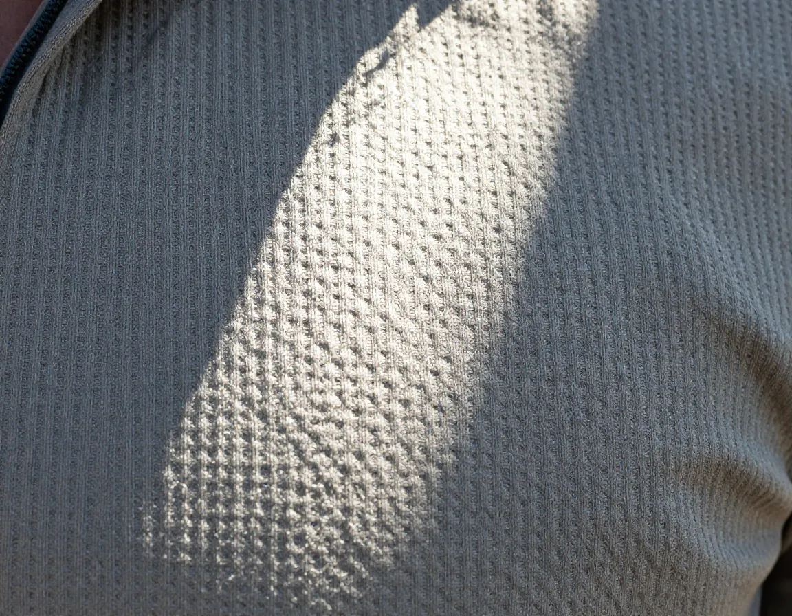 A close up of a tightly woven fabric blocking intense sunlight on a hiking shirt