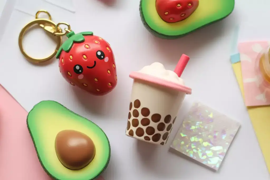 Cute keychains shaped like a smiling strawberry, avocados, and a bubble tea cup on a pastel background.