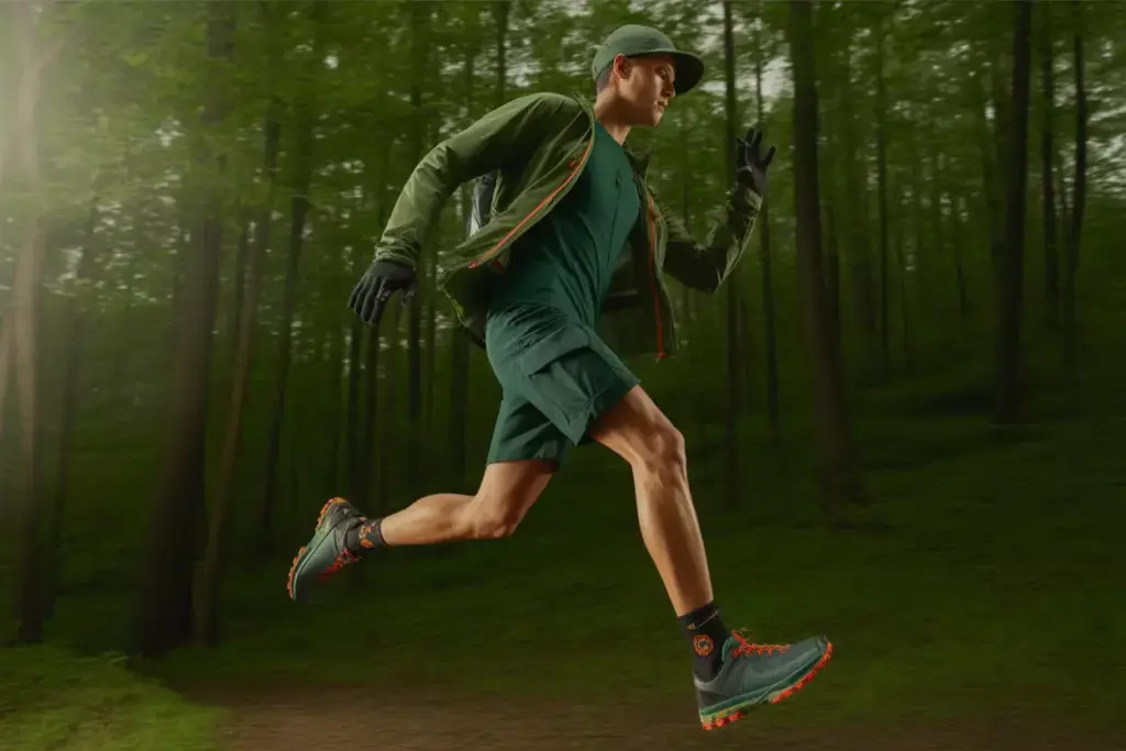 Man in athletic gear running and leaping through a green, sunlit forest.