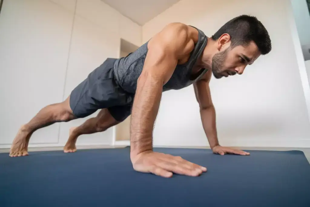 Muscular Male Hiker Performing Mountain Climbers In High Plank Position With Level Hips And Driven Knee