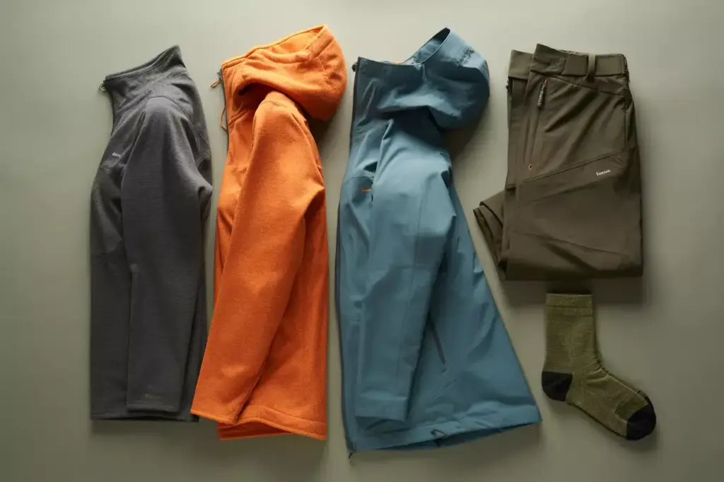 Flat Lay Of Hiking Base Layer Mid Layer And Waterproof Shell Jacket